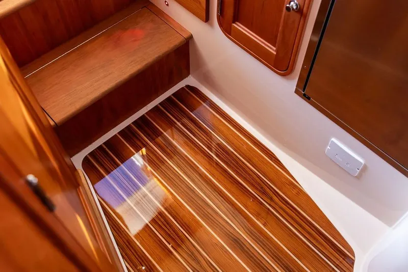 Slide: The Image of 2023 Hinckley Picnic Boat 34 S interior with polished wood flooring and cabinetry. - 20