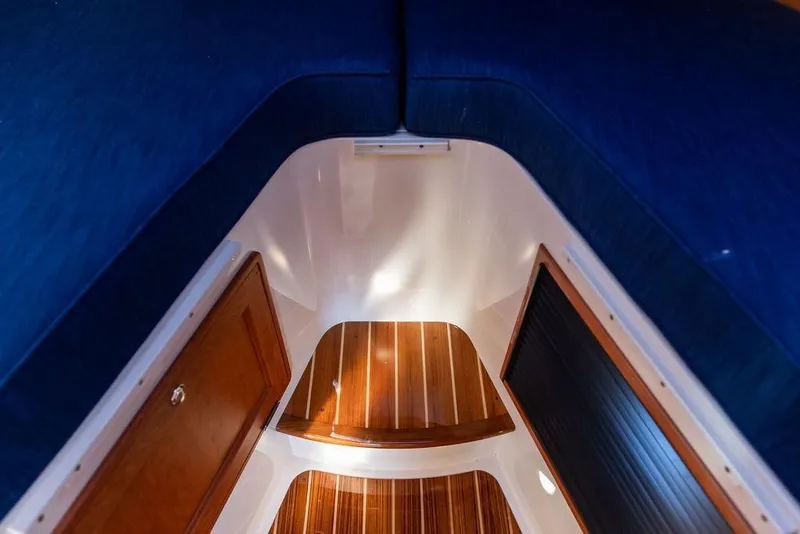 Slide: The Image of 2023 Hinckley Picnic Boat 34 S interior with wooden flooring and blue seating. - 24