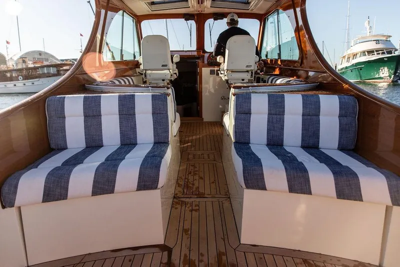 Slide: The Image of 2023 Hinckley Picnic Boat 34 S interior with striped seating and wooden flooring. - 10