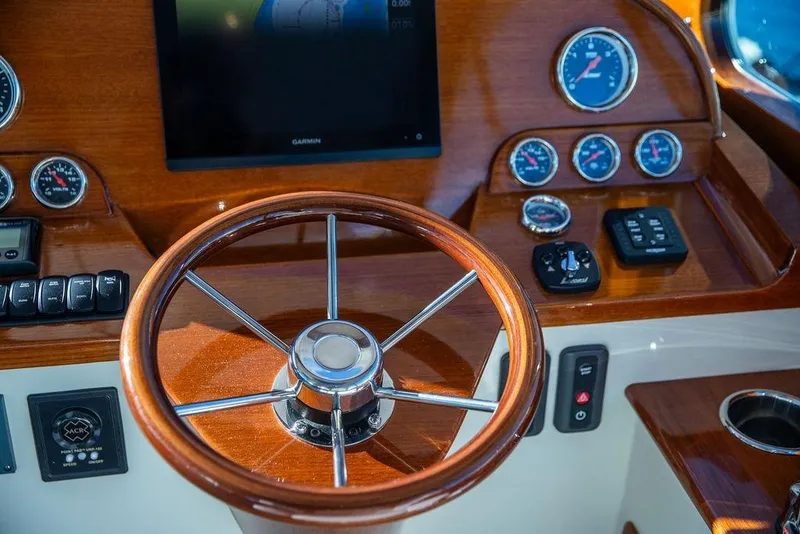 Slide: The Image of 2023 Hinckley Picnic Boat 34 S helm with wooden steering wheel and modern gauges. - 14