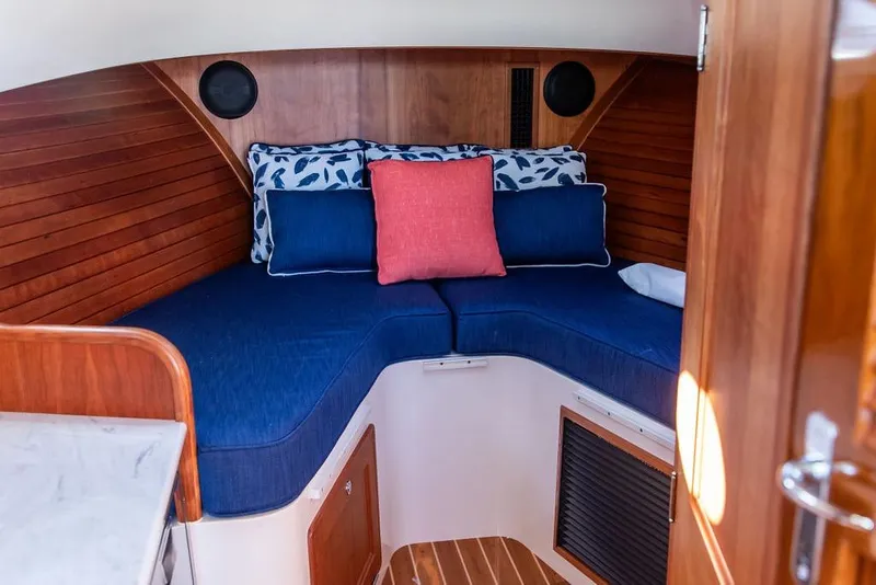Slide: The Image of 2023 Hinckley Picnic Boat 34 S cabin interior with blue cushions and wooden paneling. - 21