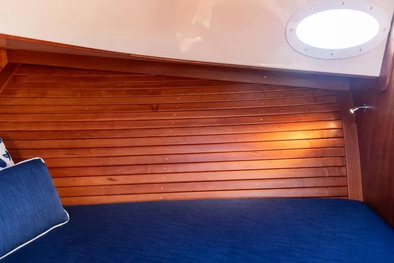 Slide: The Image of 2023 Hinckley Picnic Boat 34 S interior with wooden paneling and blue cushion. - 25