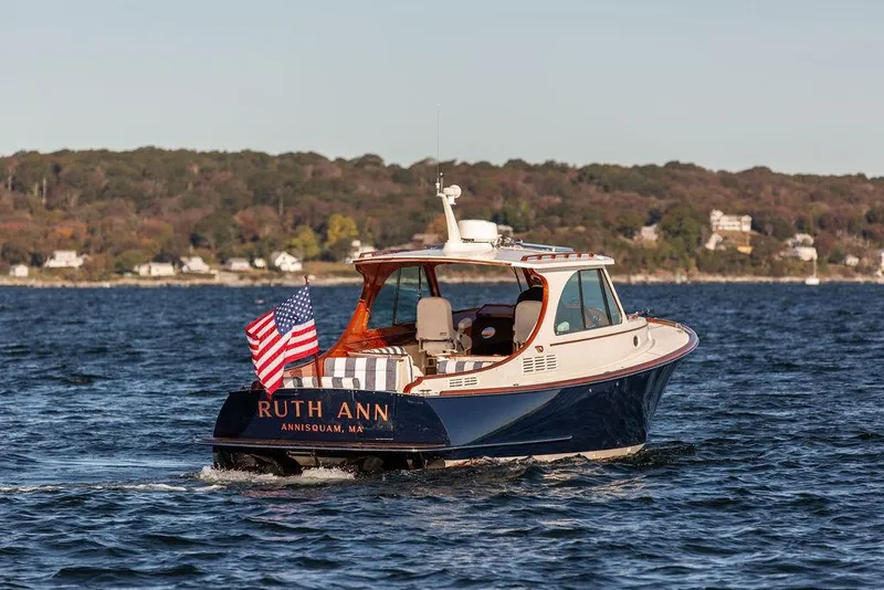 Slide: The Image of 2023 Hinckley Picnic Boat 34 S cruising on water, displaying American flag. - 4