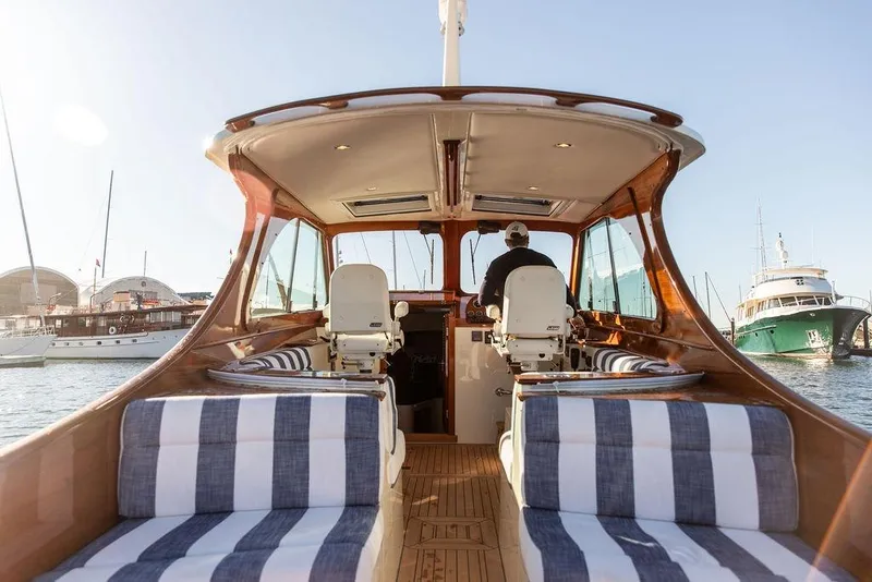 Slide: The Image of 2023 Hinckley Picnic Boat 34 S interior with striped seating, docked at marina. - 8