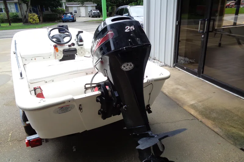 Slide: The Image of 2005 Boston Whaler 110 Sport boat with outboard motor, parked near a building. - 10