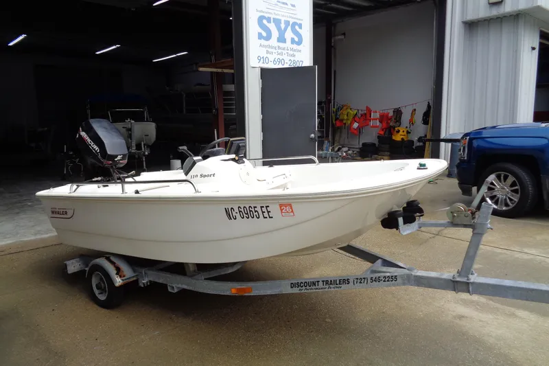 Slide: The Image of 2005 Boston Whaler 110 Sport boat on trailer, parked outside a marine service shop. - 4