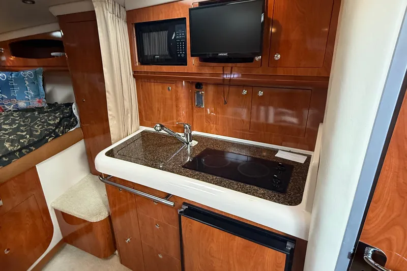 Slide: The Image of 2006 Four Winns 318 Vista yacht interior with kitchenette, microwave, and cozy sleeping area. - 24