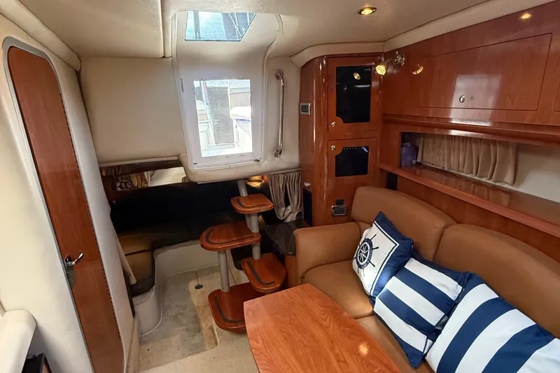 Slide: The Image of 2006 Four Winns 318 Vista cabin interior with wood accents and nautical-themed cushions. - 27