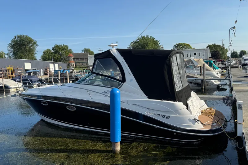 Slide: The Image of 2006 Four Winns 318 Vista boat docked at a marina, featuring a sleek black and white design. - 3