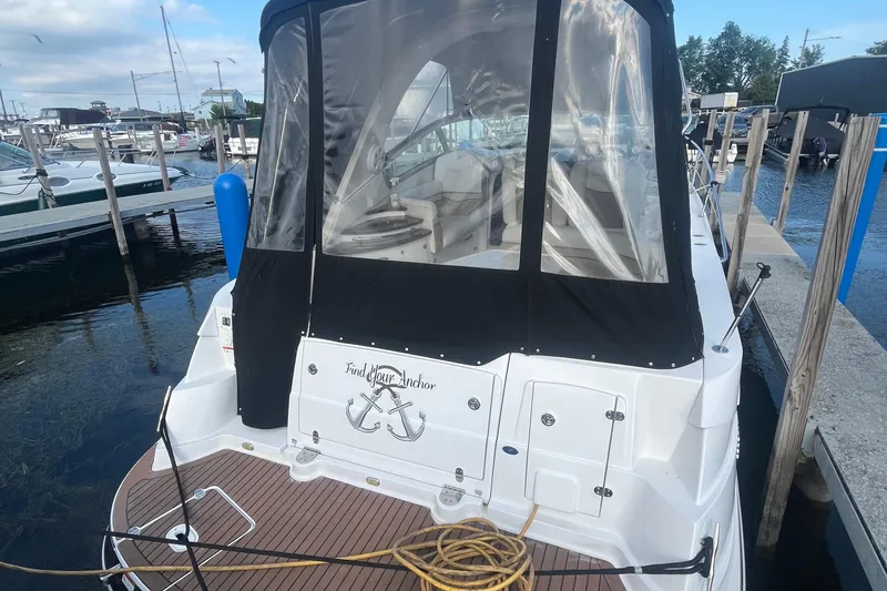 Slide: The Image of 2006 Four Winns 318 Vista boat docked, featuring a covered cockpit and wooden deck. - 7