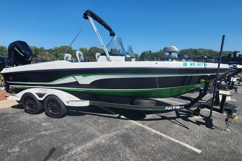 The Image of 2024 Nitro ZV21 boat with green and black design on a trailer in a parking lot. - 0