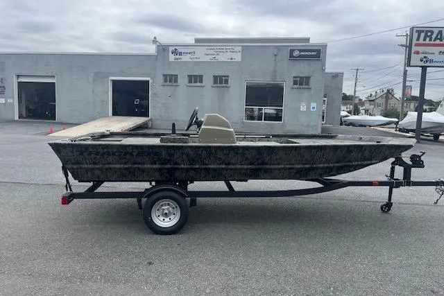 The Image of 2026 Tracker Grizzly 1648 SC boat on trailer, parked outside a service center. - 2
