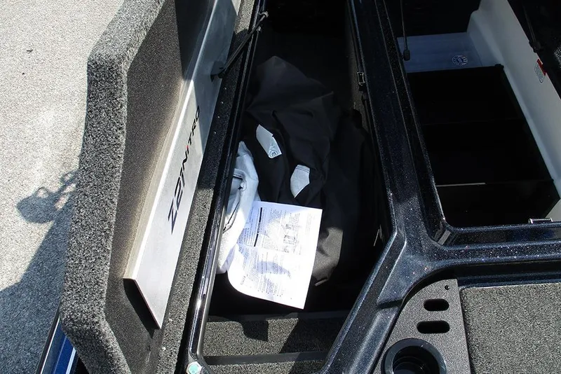 Slide: The Image of Open storage compartment of 2026 Nitro Z21 XL Pro boat with manual and gear inside. - 14