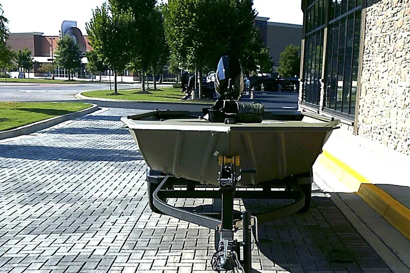 Slide: The Image of 2026 Tracker Grizzly 1654 T Sportsman boat on trailer in urban setting. - 2