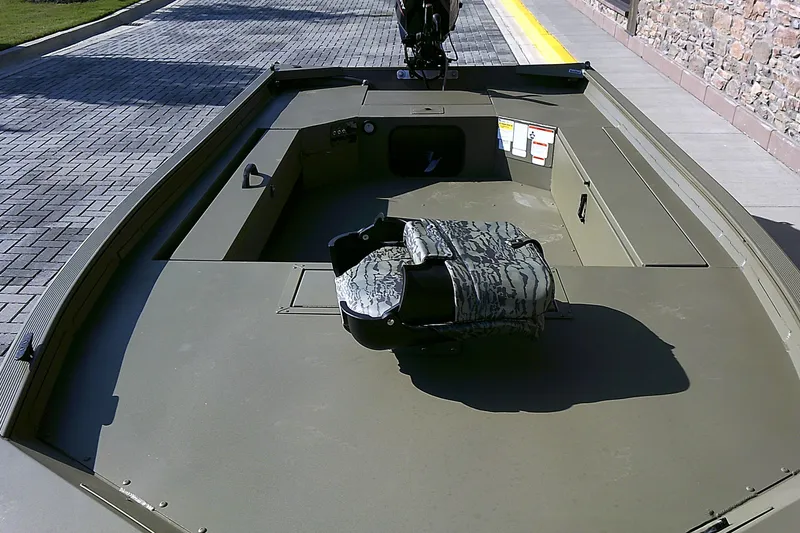Slide: The Image of 2026 Tracker Grizzly 1654 T Sportsman boat interior with camouflage seat on a paved surface. - 4