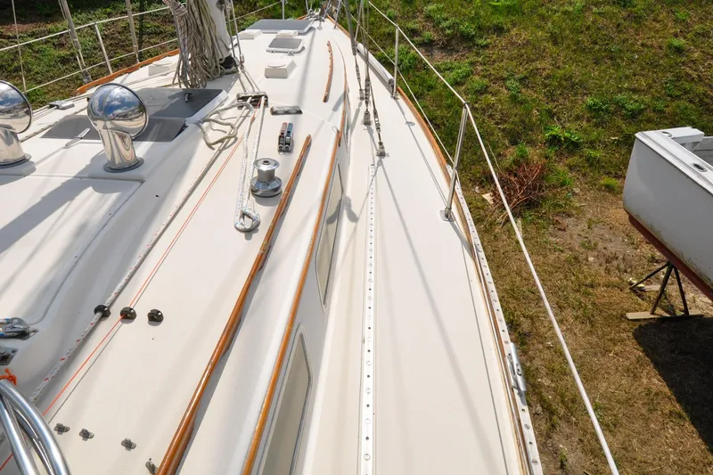 Slide: The Image of 1984 Sabre 38 MKI sailboat deck with ropes and winches, docked on grassy terrain. - 24