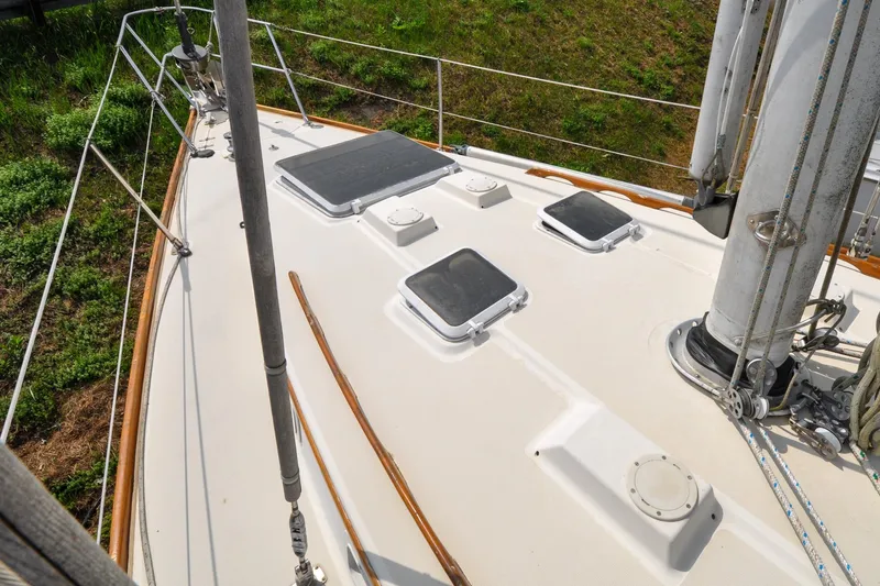 Slide: The Image of 1984 Sabre 38 MKI sailboat deck with hatches and rigging, docked on grassy shore. - 29