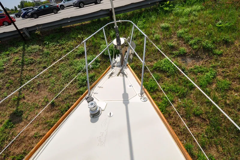 Slide: The Image of 1984 Sabre 38 MKI sailboat bow with railing, parked near grassy area. - 30