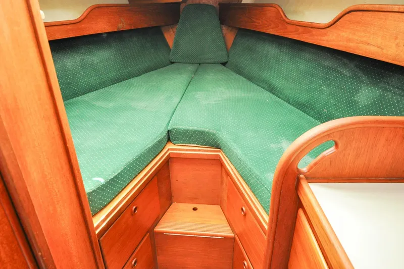 Slide: The Image of 1984 Sabre 38 MKI sailboat interior with green cushioned V-berth and wooden cabinetry. - 49