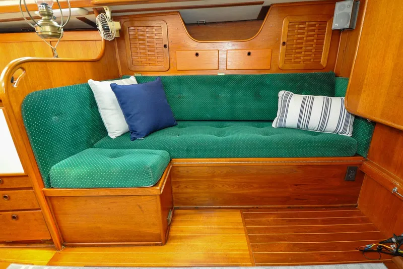 Slide: The Image of 1984 Sabre 38 MKI sailboat interior with green cushioned seating and decorative pillows. - 67