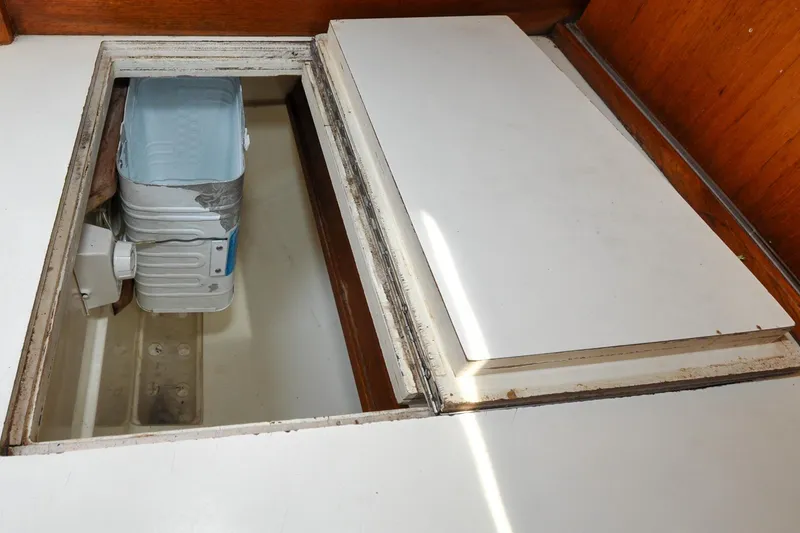 Slide: The Image of Storage compartment in 1984 Sabre 38 MKI sailboat with visible container and wooden interior. - 80