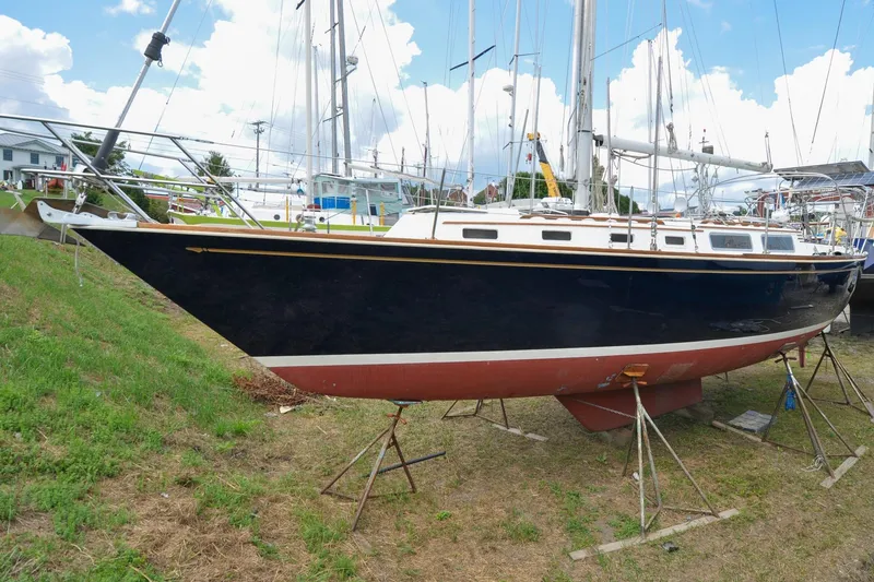 Slide: The Image of 1984 Sabre 38 MKI sailboat on land, black hull, red bottom, blue sky background. - 92