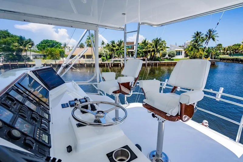 Slide: The Image of 1998 Bertram Convertible yacht helm with dual captain chairs, overlooking serene waterfront scenery. - 17