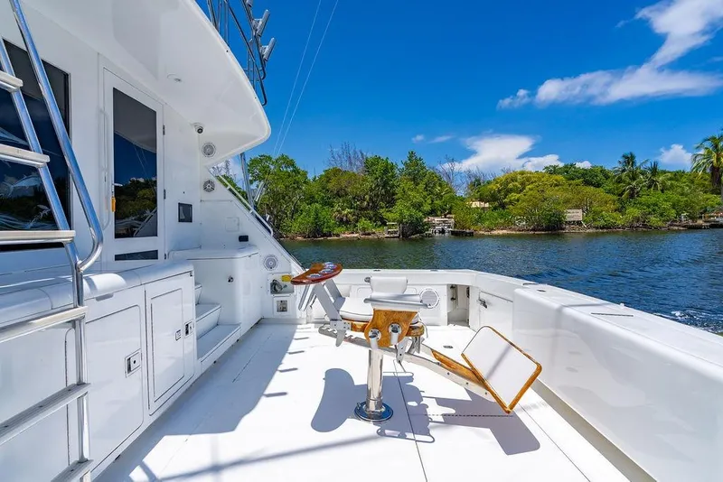 Slide: The Image of 1998 Bertram Convertible yacht deck with fishing chair, surrounded by scenic water and lush greenery. - 20