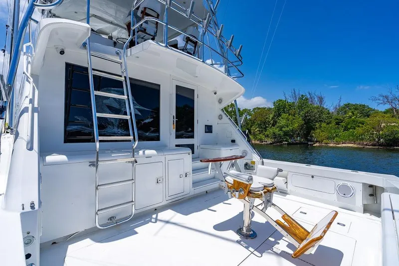 Slide: The Image of 1998 Bertram Convertible yacht deck with fishing chair, ladder, and scenic water view. - 21