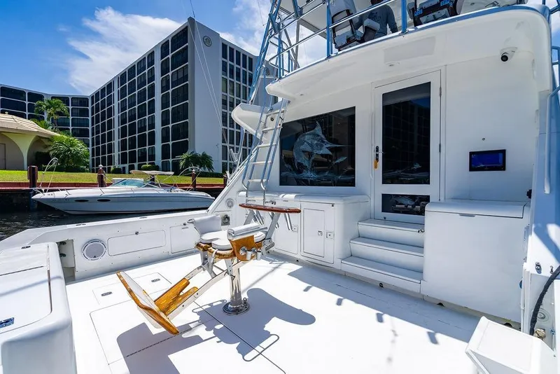Slide: The Image of 1998 Bertram Convertible yacht deck with fishing chair, docked near modern buildings. - 22