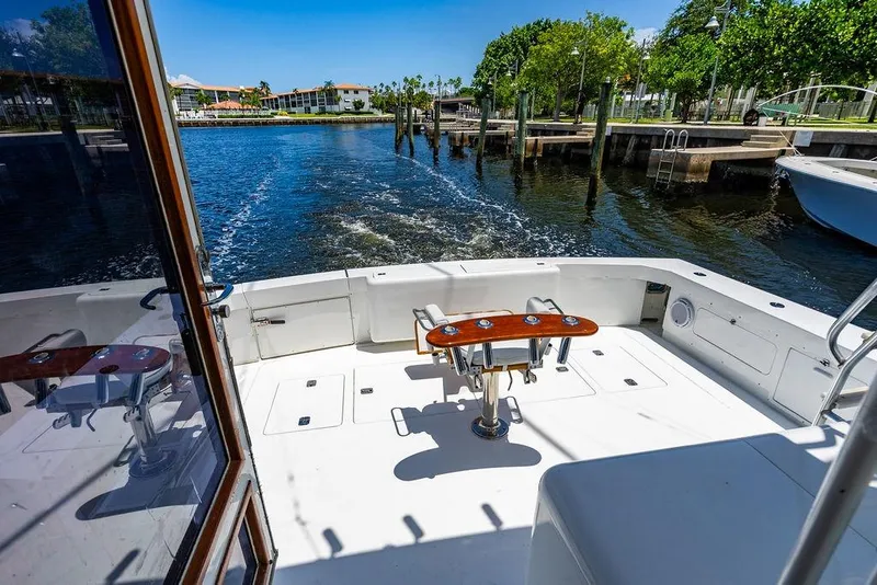 Slide: The Image of 1998 Bertram Convertible boat deck with fishing chair, docked by a scenic waterfront. - 25
