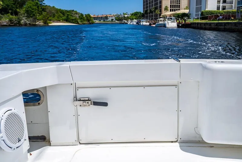 Slide: The Image of 1998 Bertram Convertible boat on a scenic waterway with lush greenery and buildings. - 26