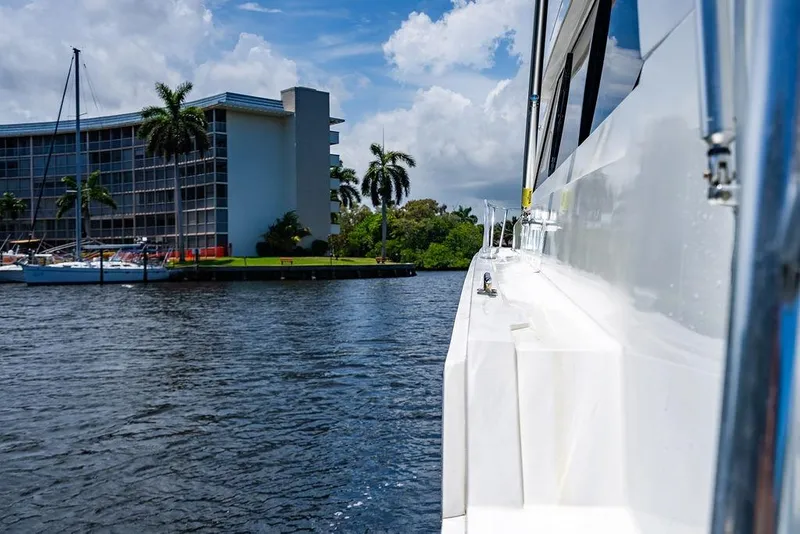 Slide: The Image of Side view of a 1998 Bertram Convertible yacht cruising near waterfront buildings and palm trees. - 27