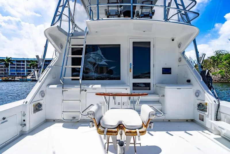Slide: The Image of 1998 Bertram Convertible yacht deck with fishing chair and ladder, docked by waterfront buildings. - 28