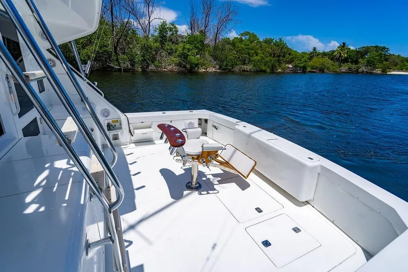 Slide: The Image of 1998 Bertram Convertible yacht deck with fishing chair, overlooking serene water and lush greenery. - 29