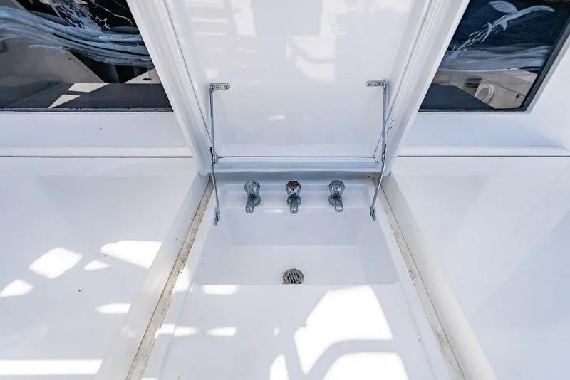 Slide: The Image of 1998 Bertram Convertible boat sink with three faucets and open lid. - 30