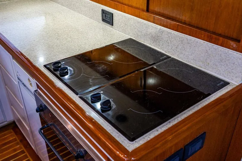 Slide: The Image of 1998 Bertram Convertible yacht kitchen with sleek electric stovetop and wooden cabinetry. - 37