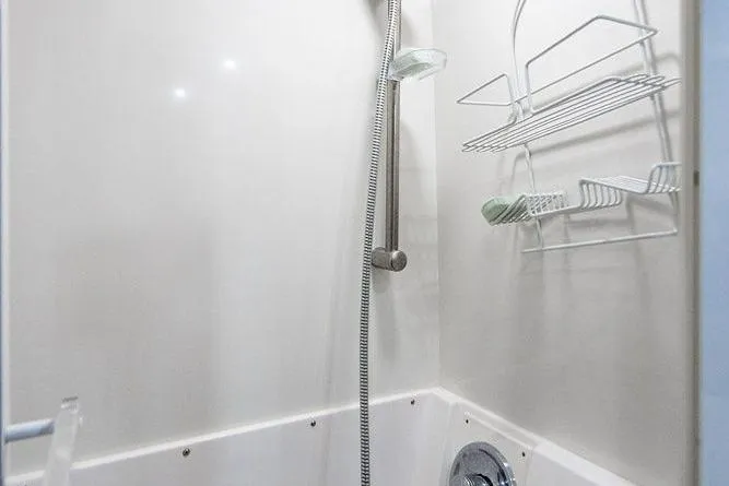 Slide: The Image of Shower area in a 1998 Bertram Convertible boat with wall-mounted caddy and handheld showerhead. - 46