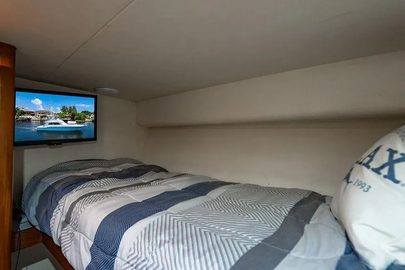 Slide: The Image of Cozy cabin interior of 1998 Bertram Convertible with bed and TV showing a boat scene. - 50