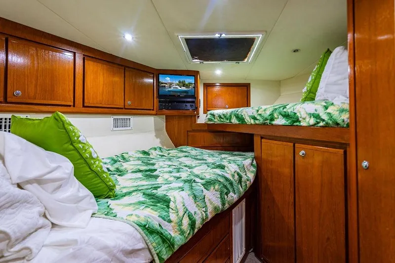 Slide: The Image of 1998 Bertram Convertible cabin with wooden cabinets, twin beds, and tropical bedding. - 53