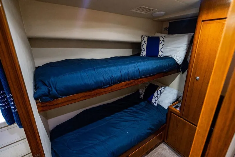 Slide: The Image of Bunk beds in 1998 Bertram Convertible yacht cabin with blue bedding and wooden accents. - 58