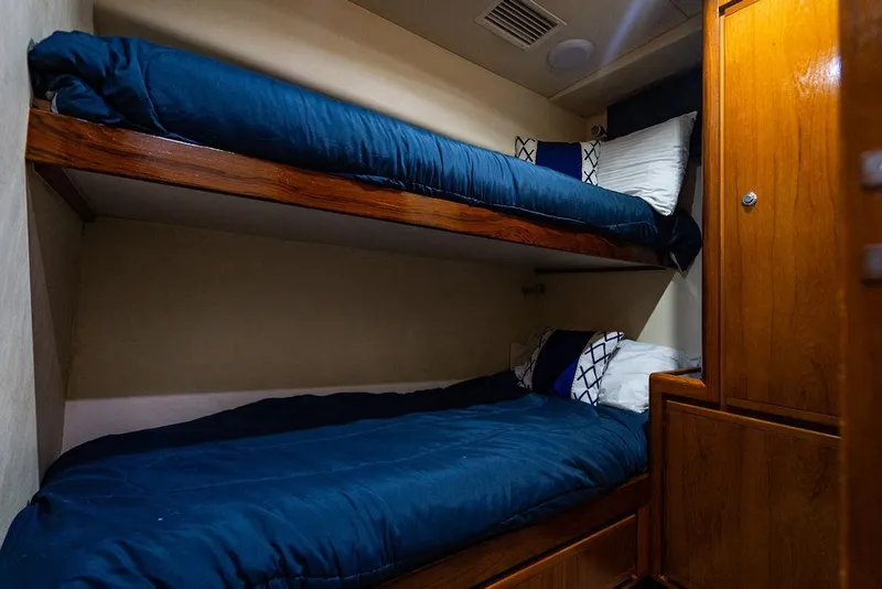Slide: The Image of 1998 Bertram Convertible yacht cabin with wooden bunk beds and blue bedding. - 59