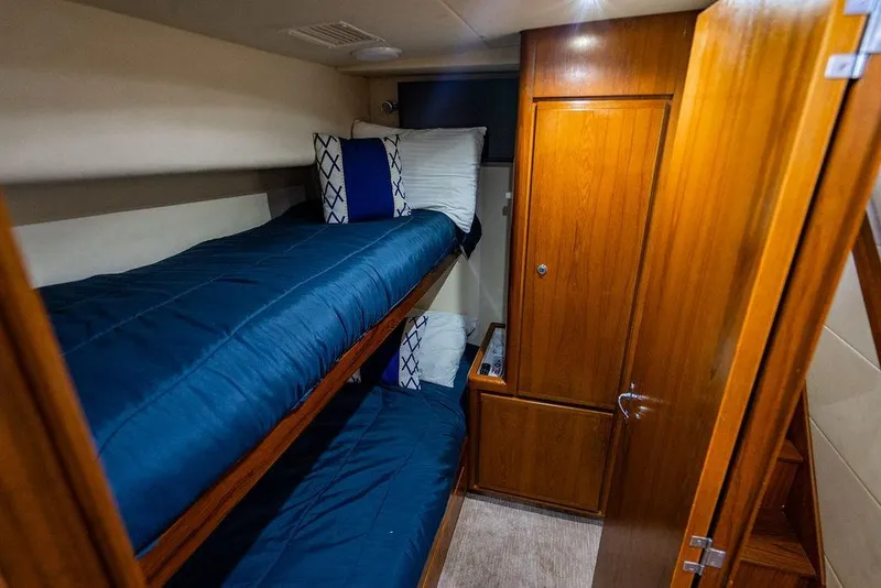 Slide: The Image of 1998 Bertram Convertible cabin with wooden interior and blue bunk beds. - 60