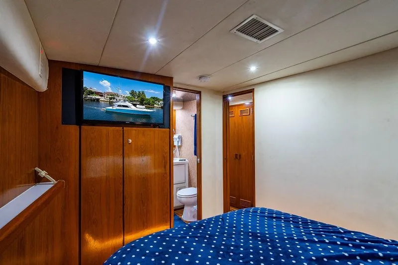 Slide: The Image of Interior of a 1998 Bertram Convertible yacht cabin with wood paneling and a polka dot bedspread. - 63