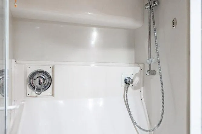 Slide: The Image of Shower area in a 1998 Bertram Convertible boat, featuring chrome fixtures and white interior. - 65
