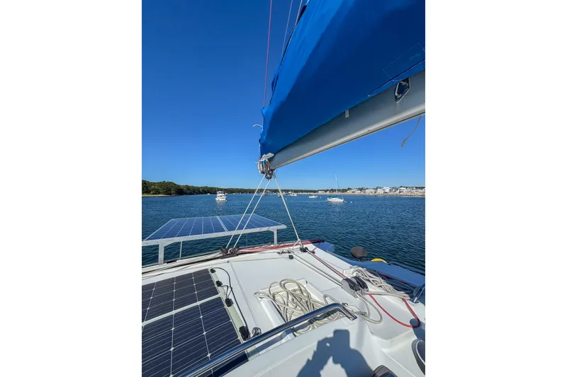 Slide: The Image of 2005 Lagoon 440 catamaran with solar panels, anchored in a scenic bay. - 10