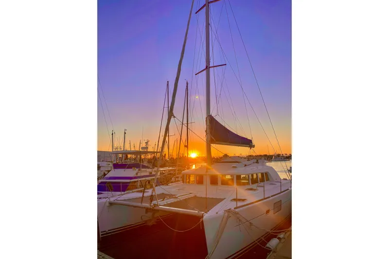 Slide: The Image of Sunset view of a 2005 Lagoon 440 catamaran docked at a marina. - 2