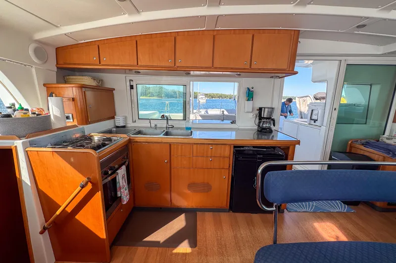Slide: The Image of Interior of 2005 Lagoon 440 catamaran kitchen with wooden cabinets and ocean view. - 24