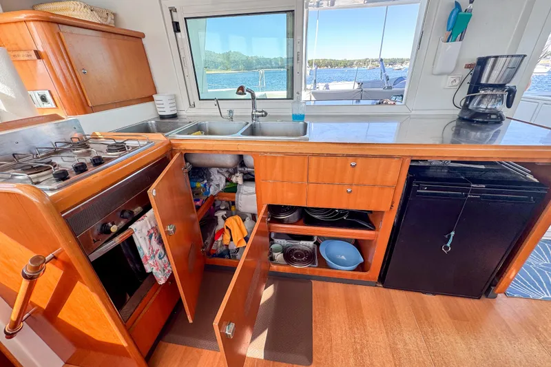Slide: The Image of Kitchen area of a 2005 Lagoon 440 catamaran with stove, sink, and storage. - 25
