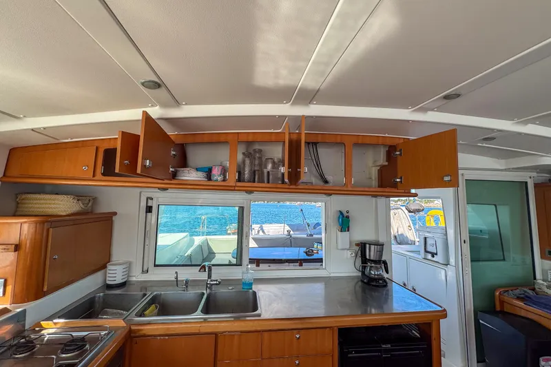 Slide: The Image of Interior of 2005 Lagoon 440 catamaran kitchen with open cabinets and ocean view. - 26
